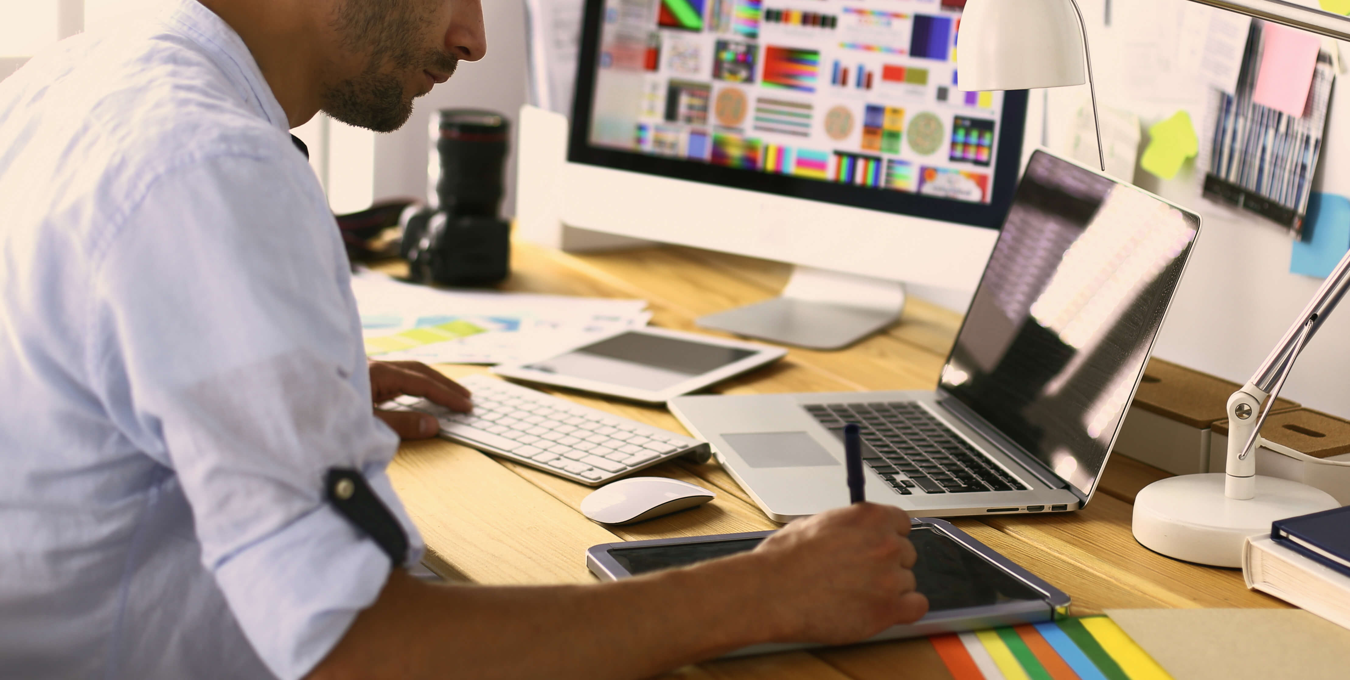 Graphic designer working on a tablet and computer.